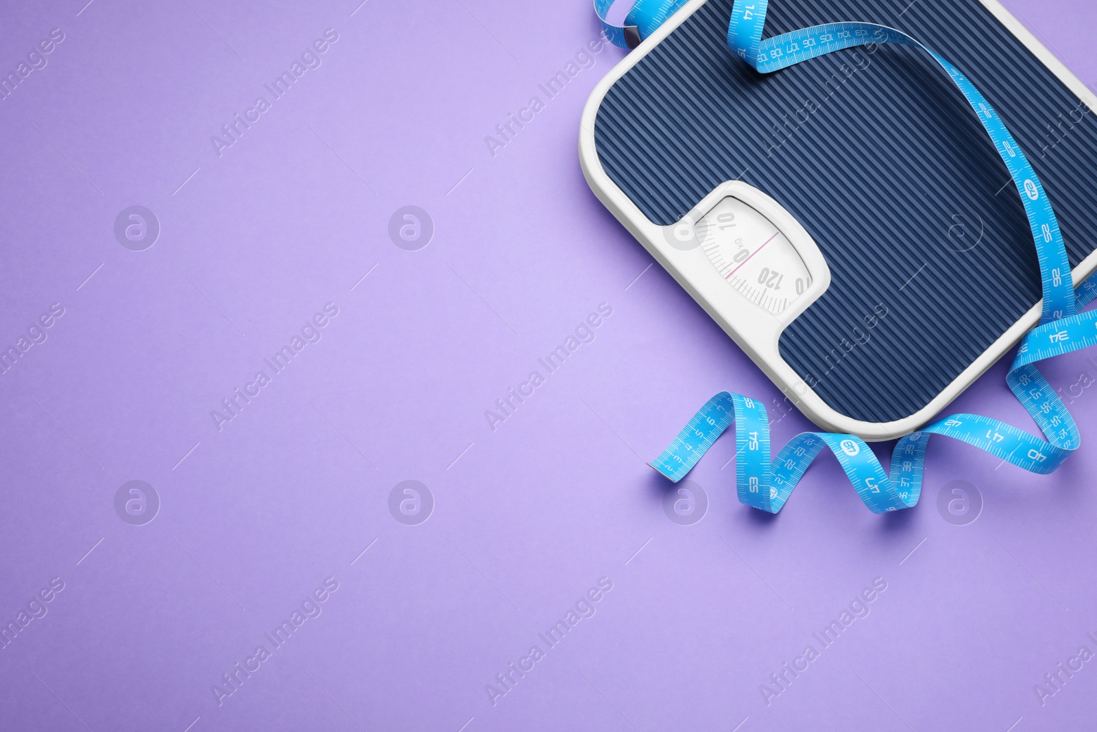 Photo of Scales and measuring tape on violet background, top view. Space for text