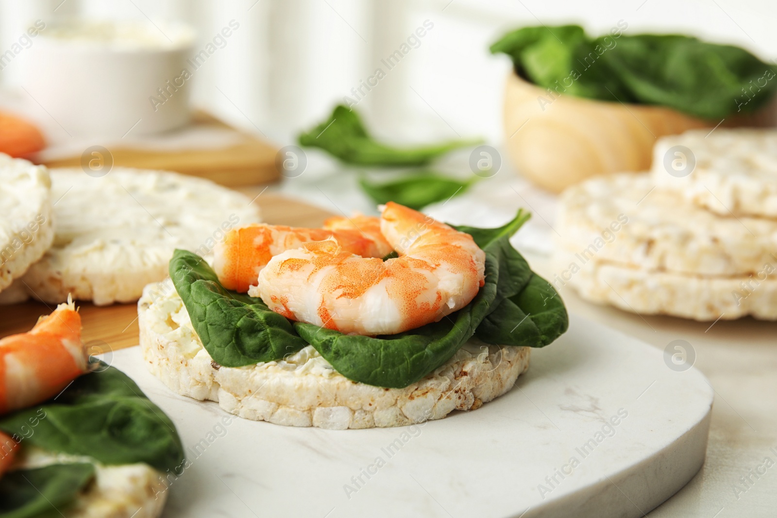 Photo of Puffed rice cakes with shrimps and basil on board, closeup