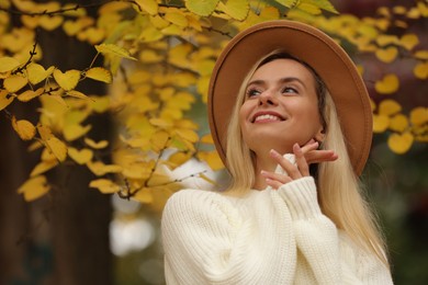 Photo of Portrait of happy woman in autumn park. Space for text