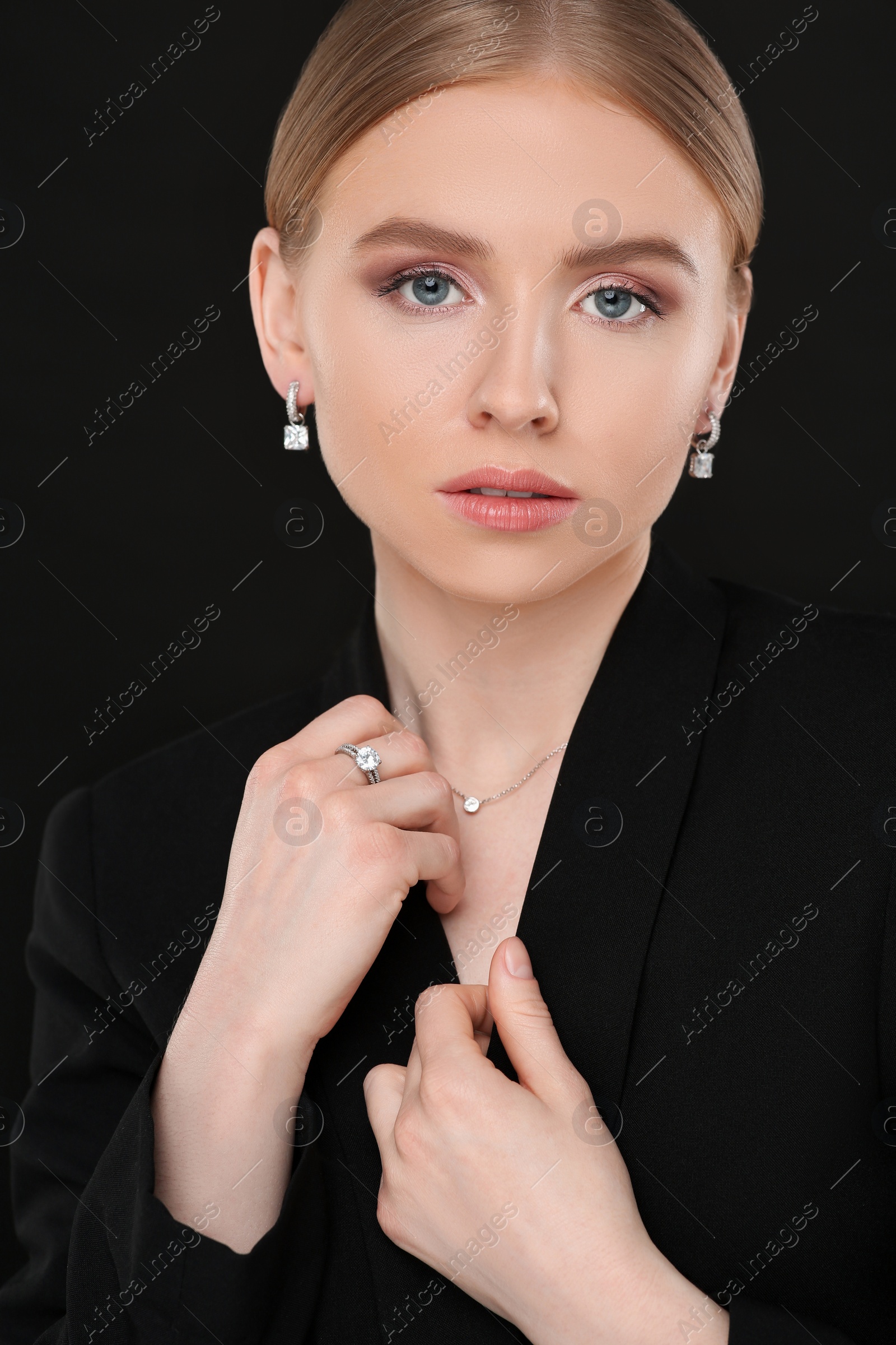 Photo of Beautiful young woman with elegant jewelry on black background