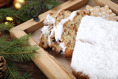 Traditional Christmas Stollen with icing sugar on wooden table, closeup