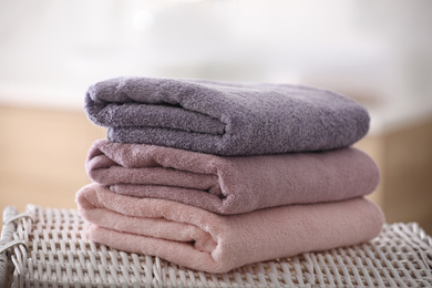 Photo of Stack of fresh towels on wicker stand in bathroom