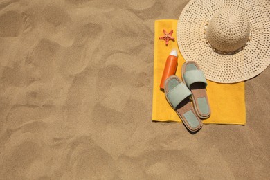 Sunscreen, starfish and beach accessories on sand, top view with space for text. Sun protection care