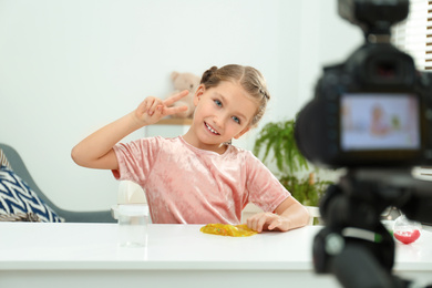 Photo of Cute little blogger with slime recording video at home