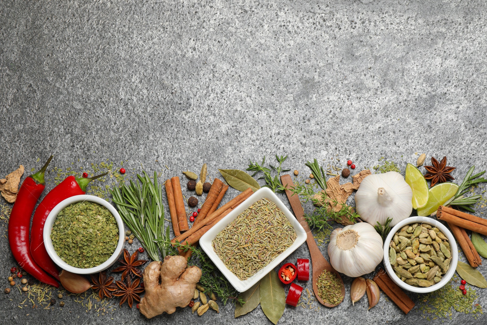 Photo of Flat lay composition with different natural spices and herbs on grey table, space for text