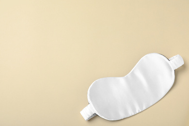 Photo of White sleeping mask on yellow background, top view with space for text. Bedtime accessory