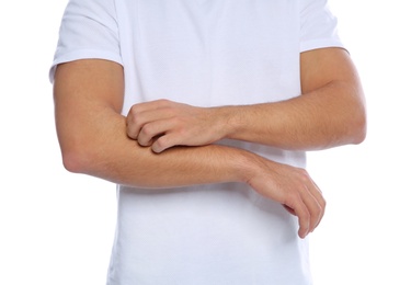 Photo of Young man scratching arm on white background, closeup. Annoying itch