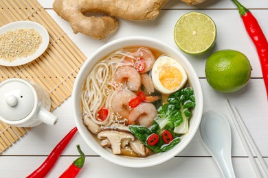 Photo of Tasty ramen with shrimps in bowl and ingredients on white wooden table, flat lay