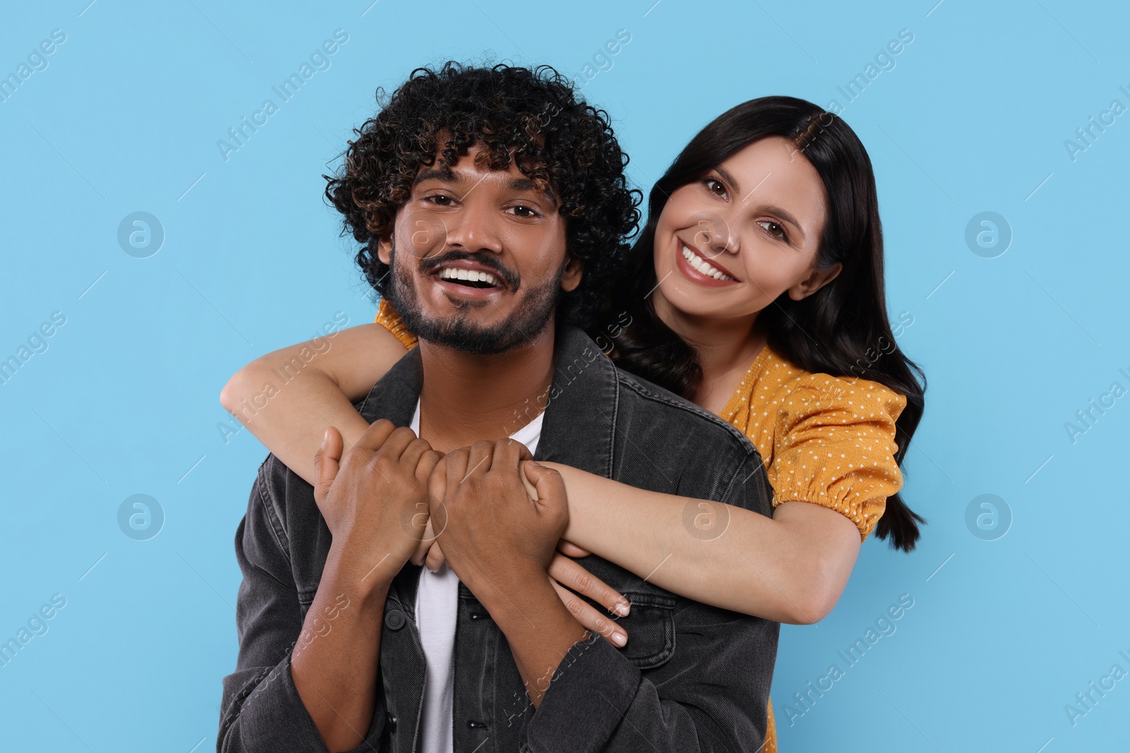 Photo of International dating. Happy couple hugging on light blue background