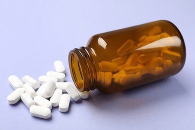 Bottle and vitamin capsules on violet background