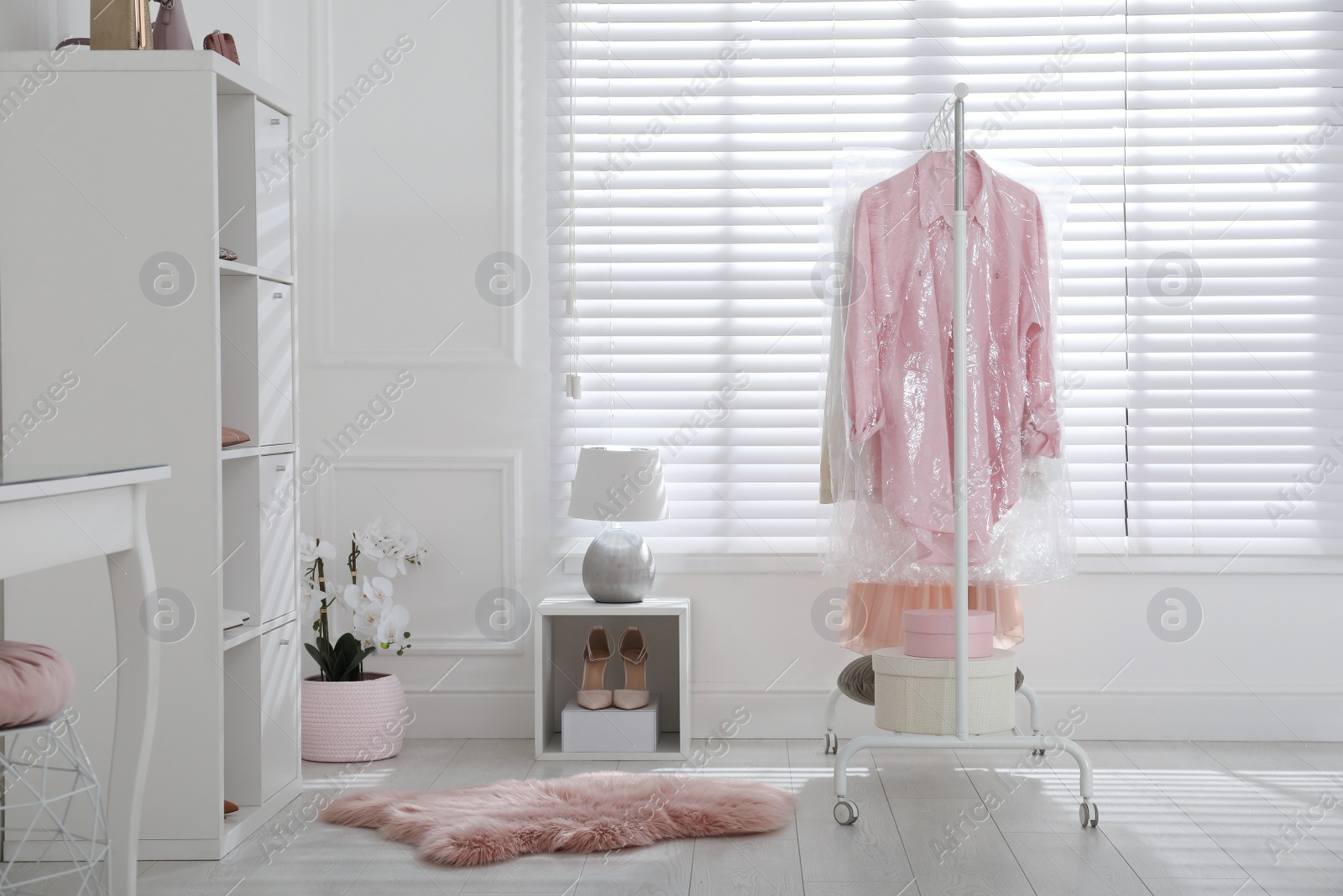 Photo of Rack with clothes in plastic bags indoors