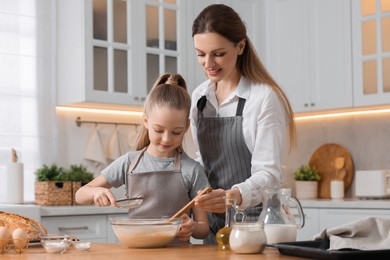 Making bread. Mother and her daughter preparing dough in bowl at wooden table in kitchen