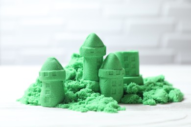 Castle figures made of green kinetic sand on white table, closeup