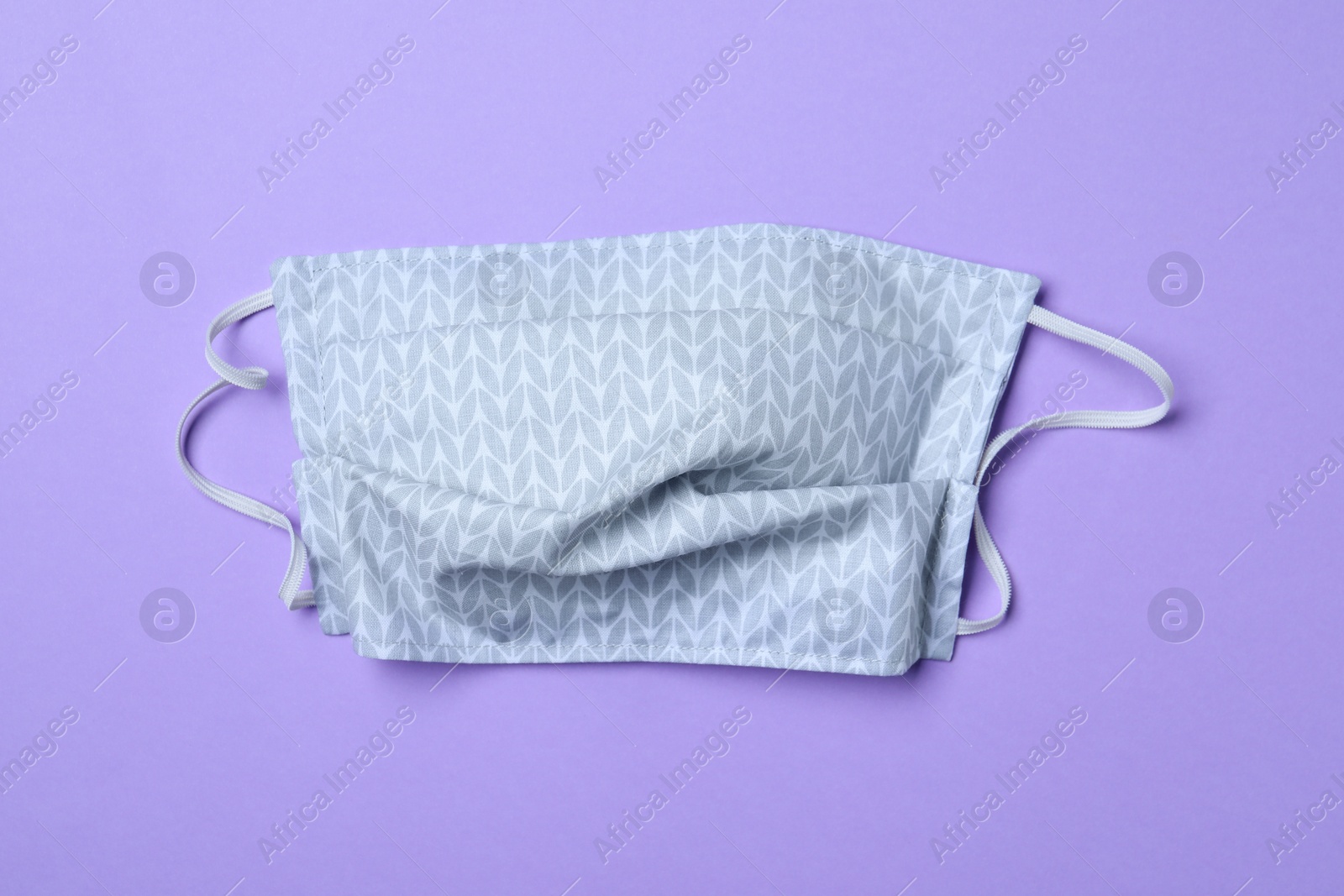 Photo of Homemade protective mask on violet background, top view. Sewing idea