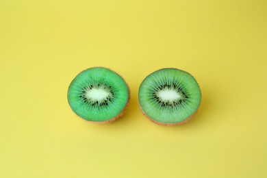 Photo of Cut fresh ripe kiwis on yellow background, above view