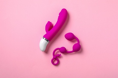 Photo of Anal balls and vibrator on pink background, flat lay. Sex toys