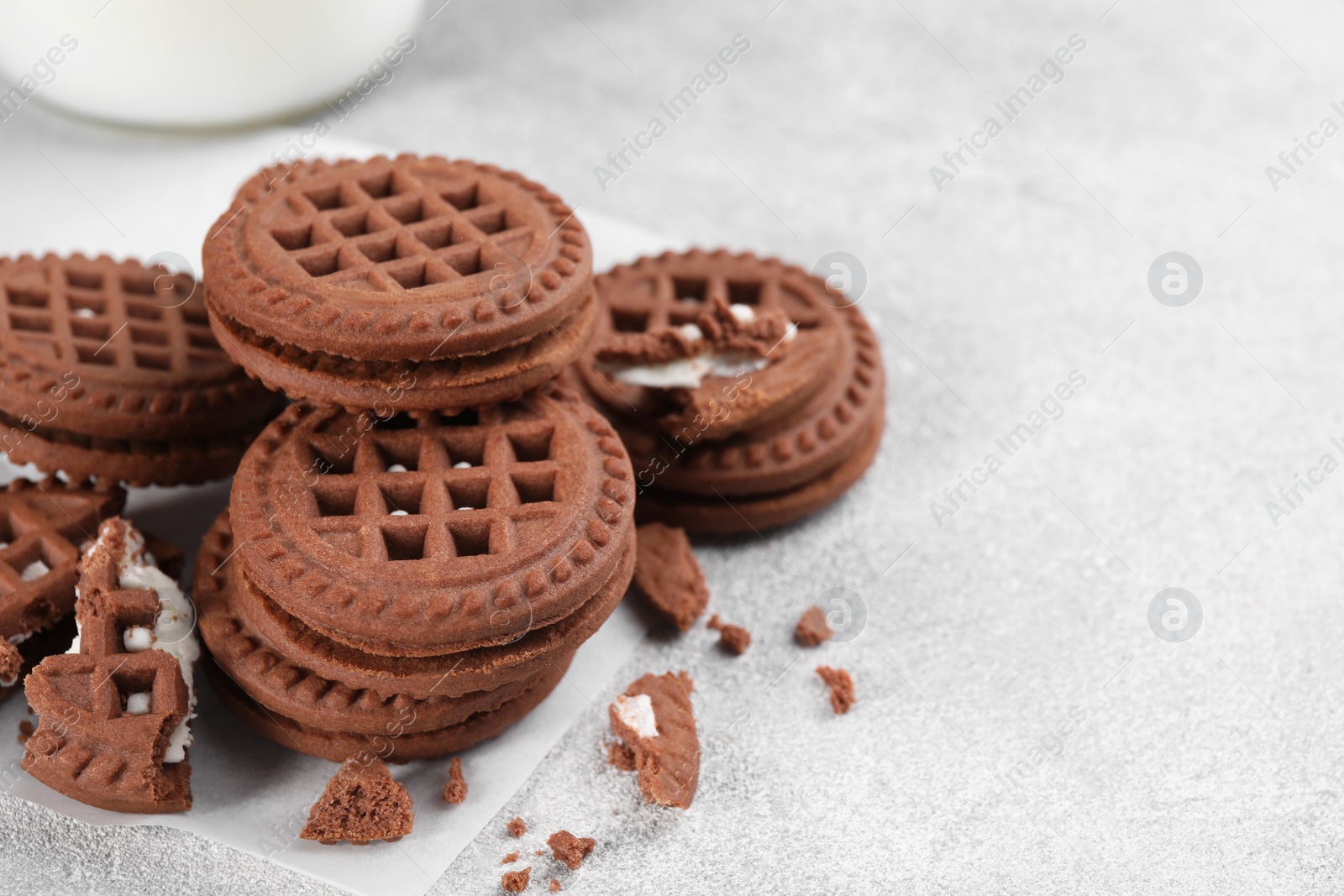 Photo of Tasty chocolate sandwich cookies with cream on light grey table, space for text