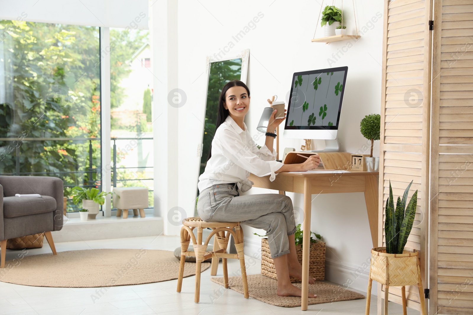 Photo of Young woman working at table in light room. Home office