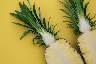 Halves of ripe pineapple on yellow background, flat lay