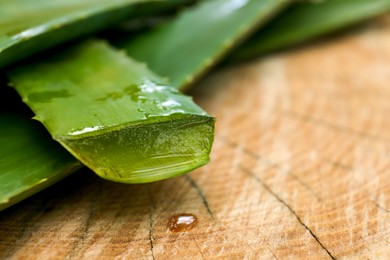 Fresh cut aloe vera leaves with dripping juice on wooden stump, closeup. Space for text