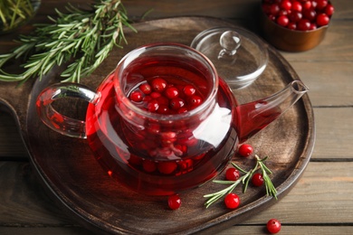 Photo of Tasty hot cranberry tea and fresh ingredients on wooden table
