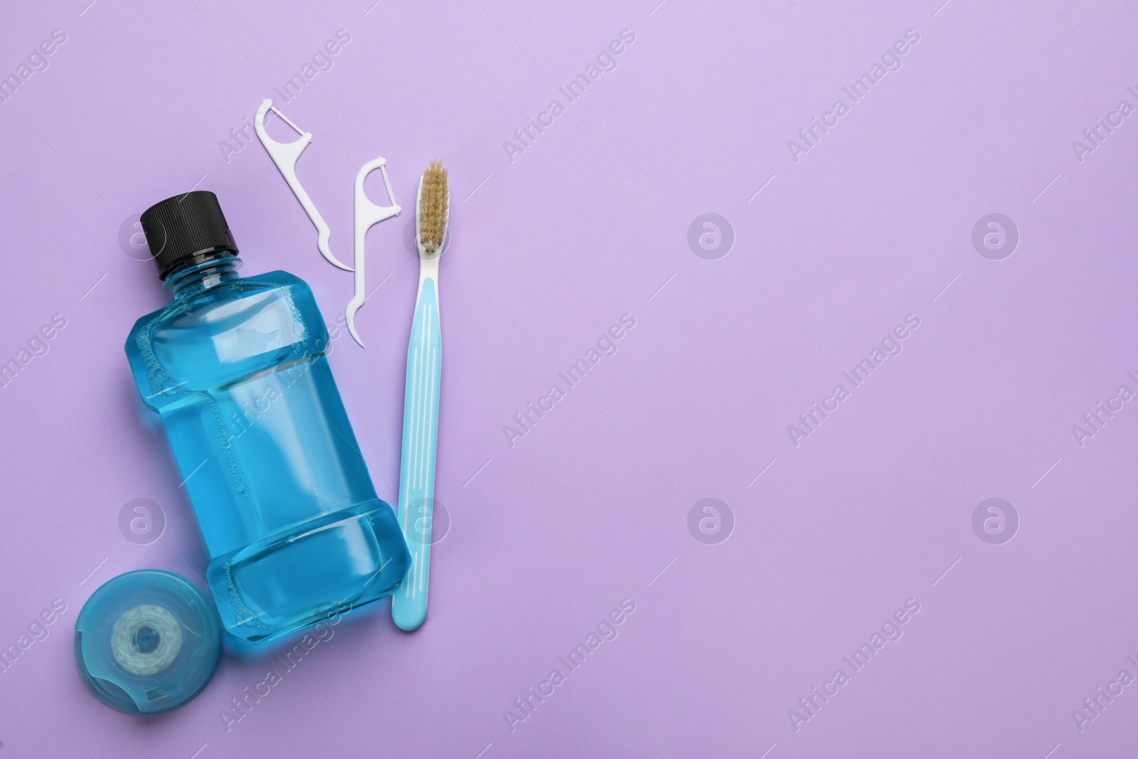 Photo of Mouthwash, toothbrush and dental floss on violet background, flat lay. Space for text