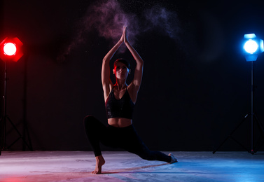 Photo of Professional acrobat with chalk powder exercising in dark studio