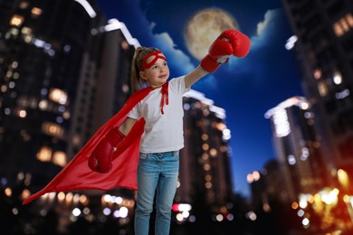 Image of Little girl wearing superhero costume and beautiful cityscape in night on background