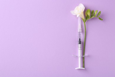 Photo of Cosmetology. Medical syringe and freesia flower on violet background, top view. Space for text