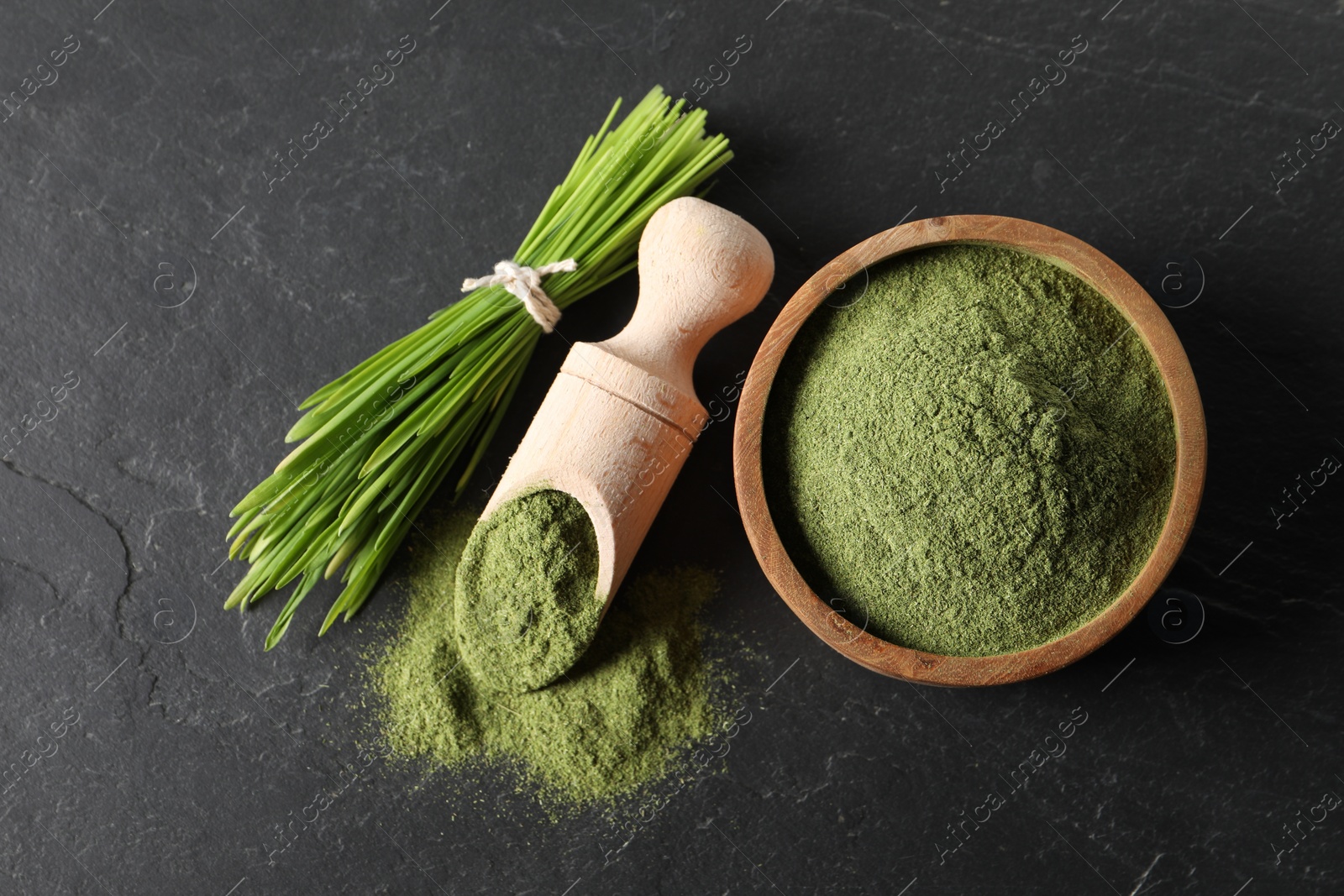 Photo of Wheat grass powder and fresh sprouts on grey textured table, flat lay