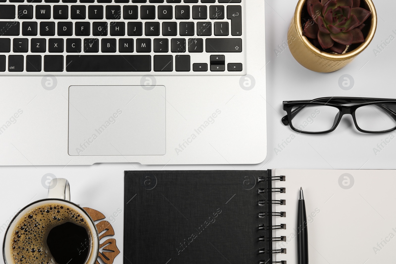 Photo of Modern laptop, notebook, pen, houseplant, glasses and cup of coffee on white background, flat lay