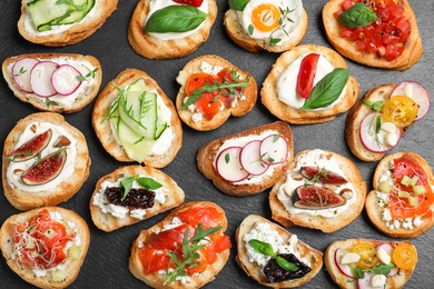 Different bruschettas on black background, flat lay