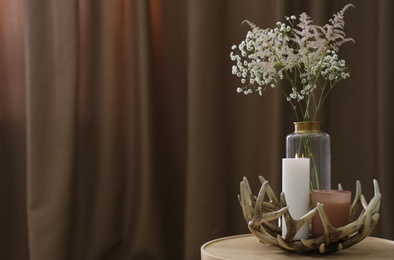 Photo of Vase with beautiful flowers and candles on table indoors, space for text. Interior elements
