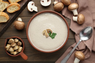 Delicious mushroom cream soup with parsley served on light grey wooden table, flat lay