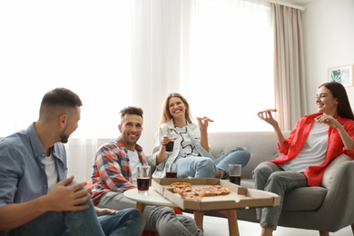 Group of friends eating tasty pizza at home