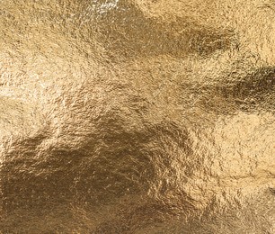 Textured golden foil as background, top view