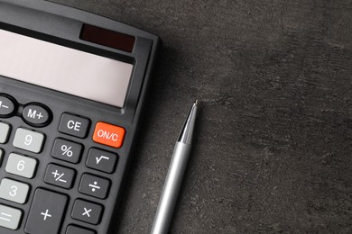 Calculator and pen on dark gray table, flat lay with space for text