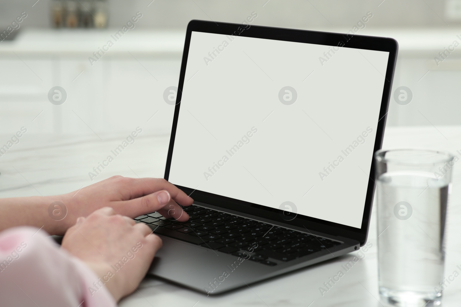 Photo of Woman using laptop at white table indoors, closeup