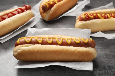 Photo of Delicious hot dogs with mustard and ketchup on grey table, closeup