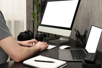 Photographer working on computer at dark table with camera, closeup