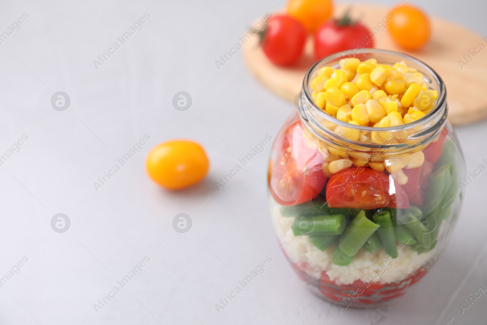 Photo of Healthy salad in glass jar on light table. Space for text