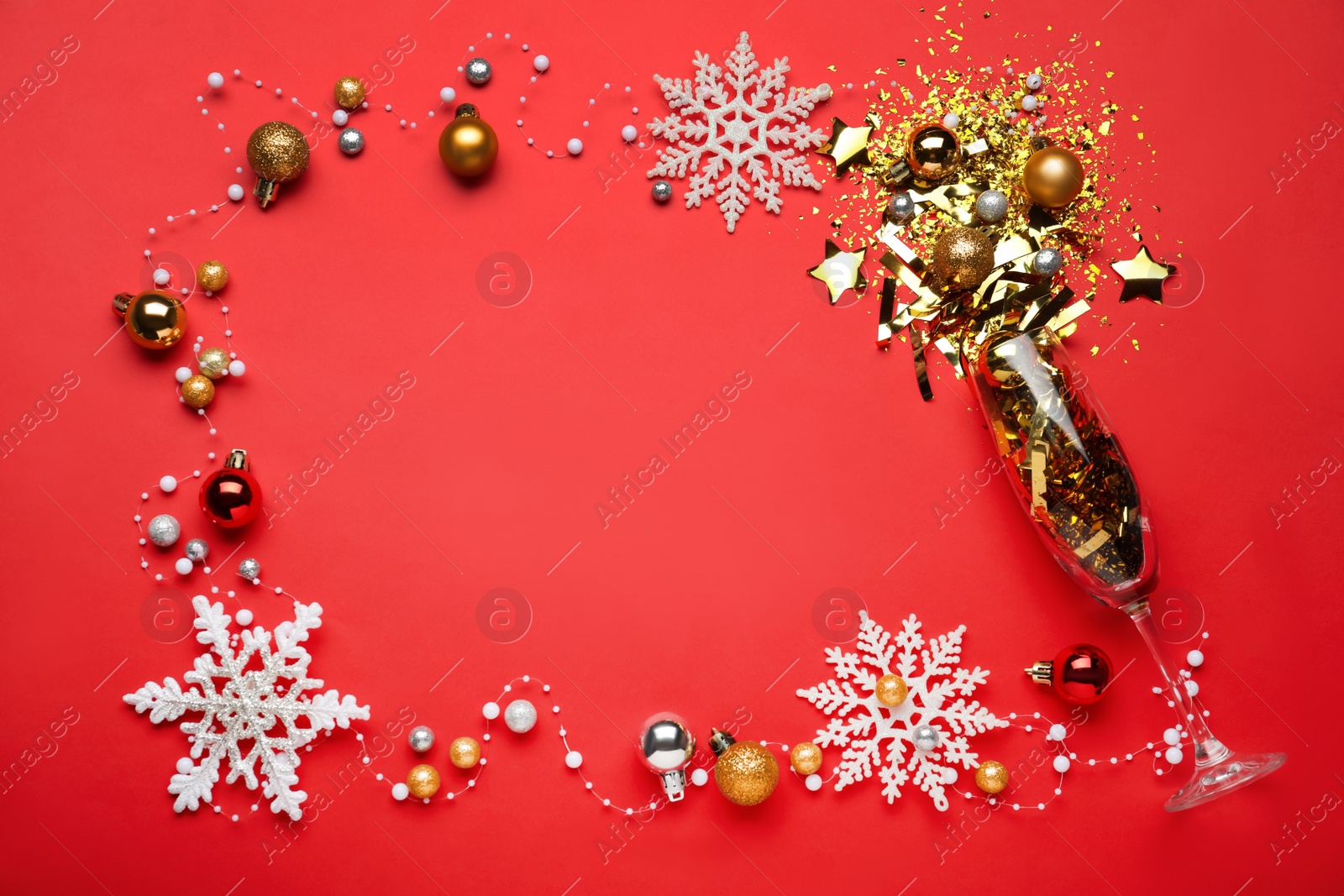 Photo of Frame made of confetti, festive decor and champagne glass on red background, flat lay. Space for text