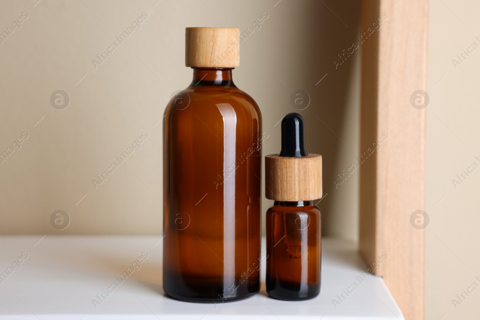 Photo of Glass bottles of cosmetic products on white shelf