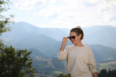 Photo of Woman with sunglasses in mountains. Space for text