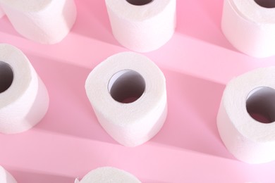 Photo of Many soft toilet paper rolls on pink background, above view