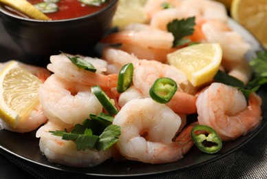 Photo of Tasty boiled shrimps with cocktail sauce, chili, parsley and lemon on table, closeup