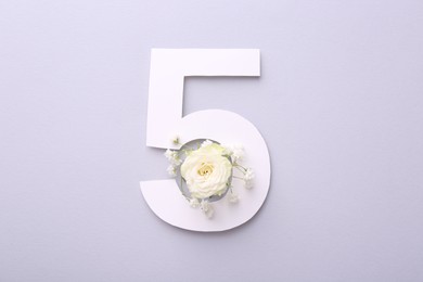 Photo of Paper number 5 and beautiful flowers on light grey background, top view