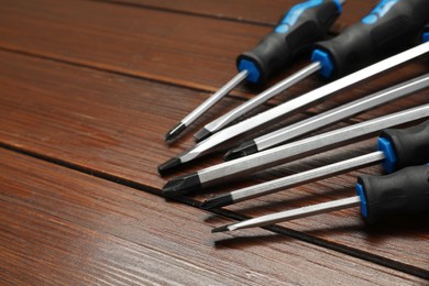 Photo of Set of screwdrivers on wooden table, closeup. Space for text