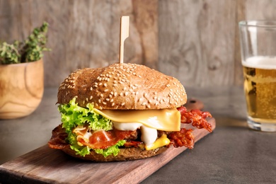 Photo of Tasty burger with bacon on wooden board