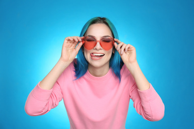 Photo of Young woman with bright dyed hair on light blue background